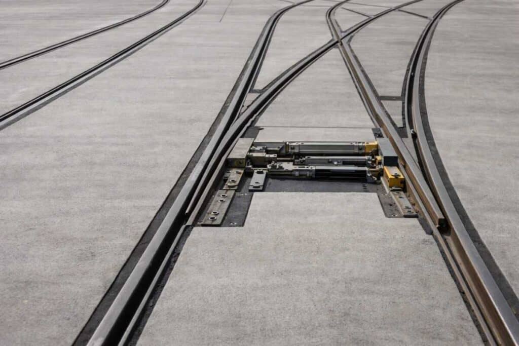 Light rail track infrastructure showing rail, switch mechanism, and embedded street-level guideway with flangeway gap