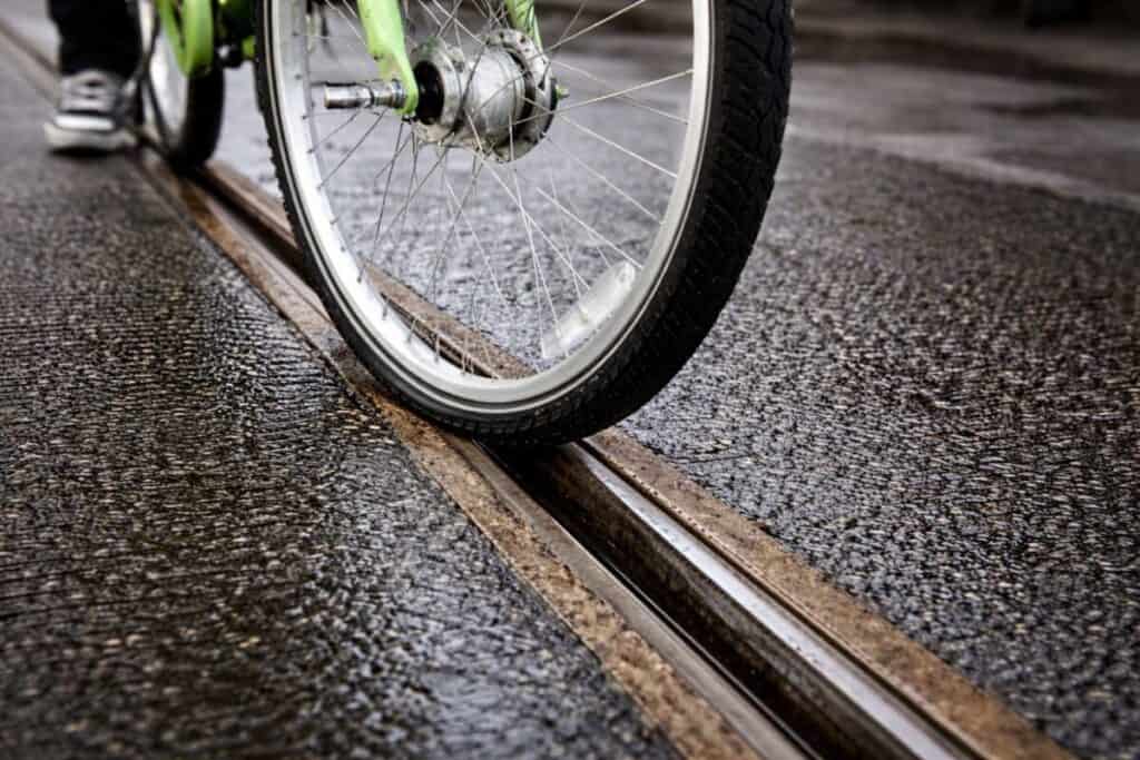 Close-up of bicycle wheel entering embedded rail flangeway gap showing entrapment risk