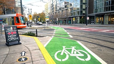Light rail track embedded in urban street with bike lane intersection, daytime