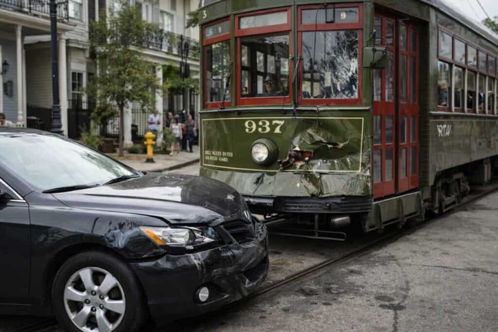 Green New Orleans style streetcar with minor front end damage after low speed collision with motor vehicle on historic street